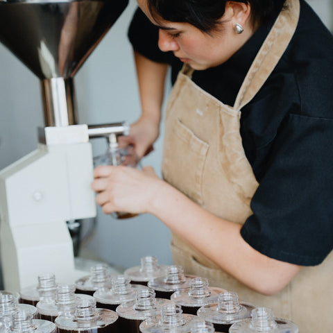 person pumping body wash from a hopper into a bottle