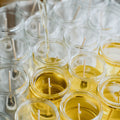 Clear glass jars with lit candles being filled with wax