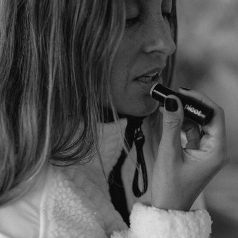 Black and white photo of a person applying lip balm with a blurred background
