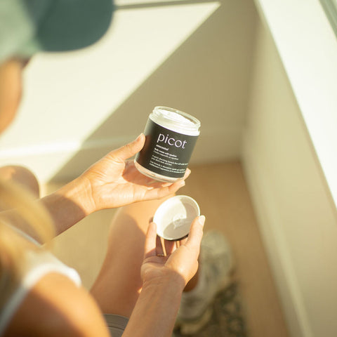 woman holding a jar of picot cream in a sunbeam
